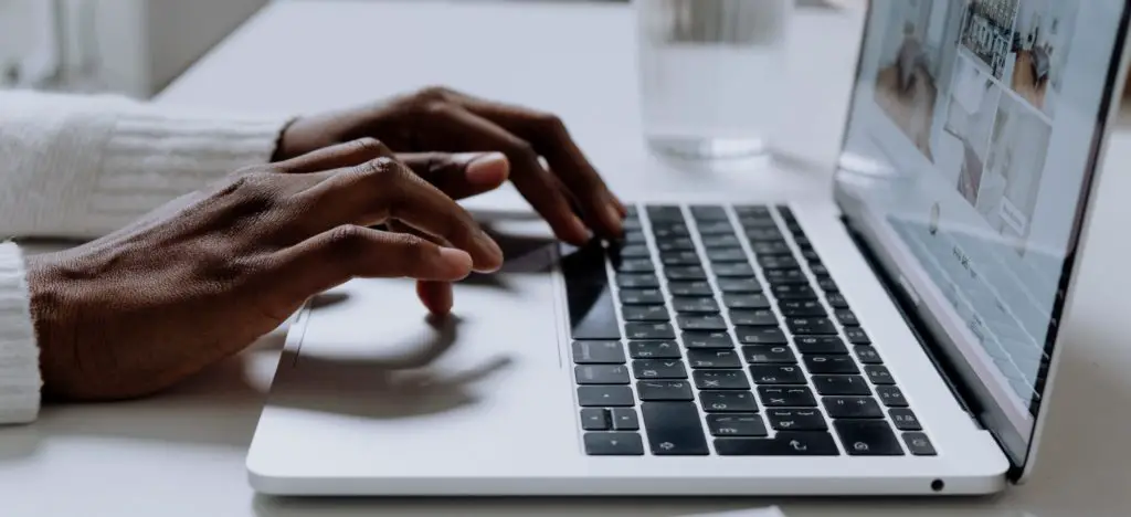Person typing on a white laptop