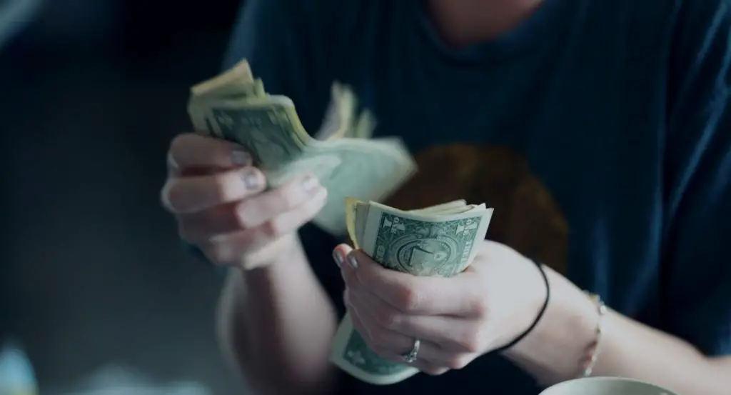 A twenty-four year old woman counting dollar bills.