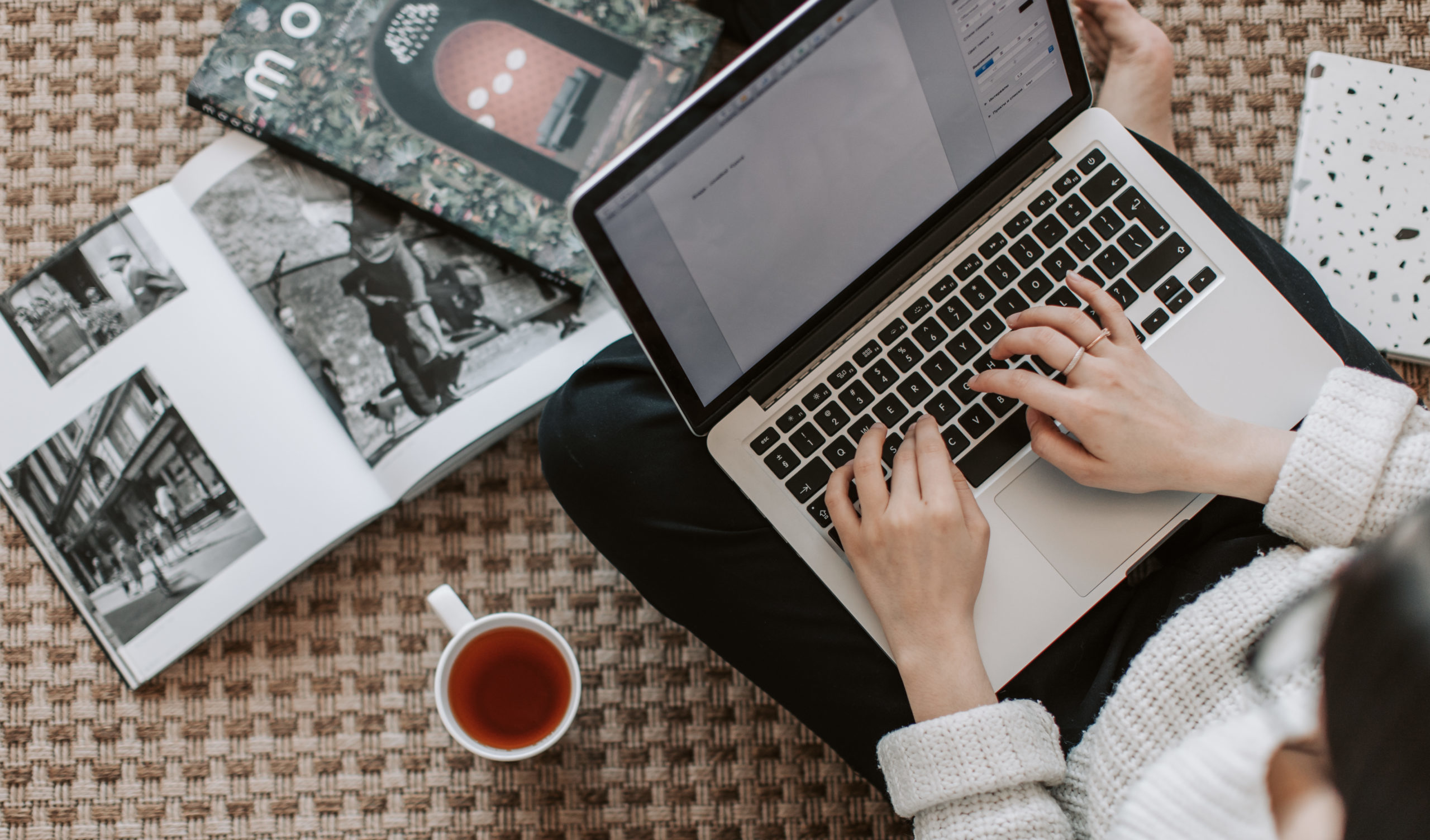 Crop young businesswoman using laptop while drinking tea at home