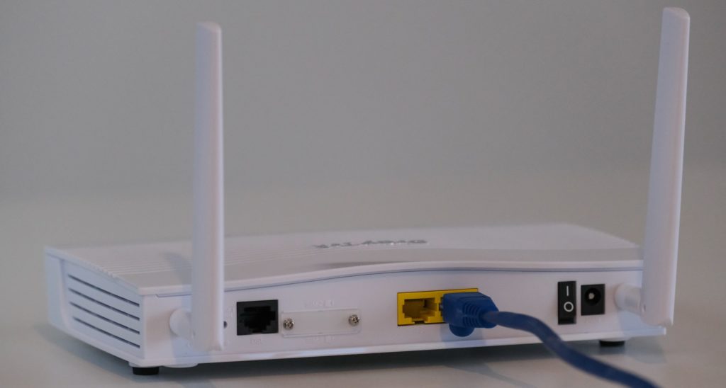 Broadband internet router with ethernet cable plugged in to the back in the ethernet port.