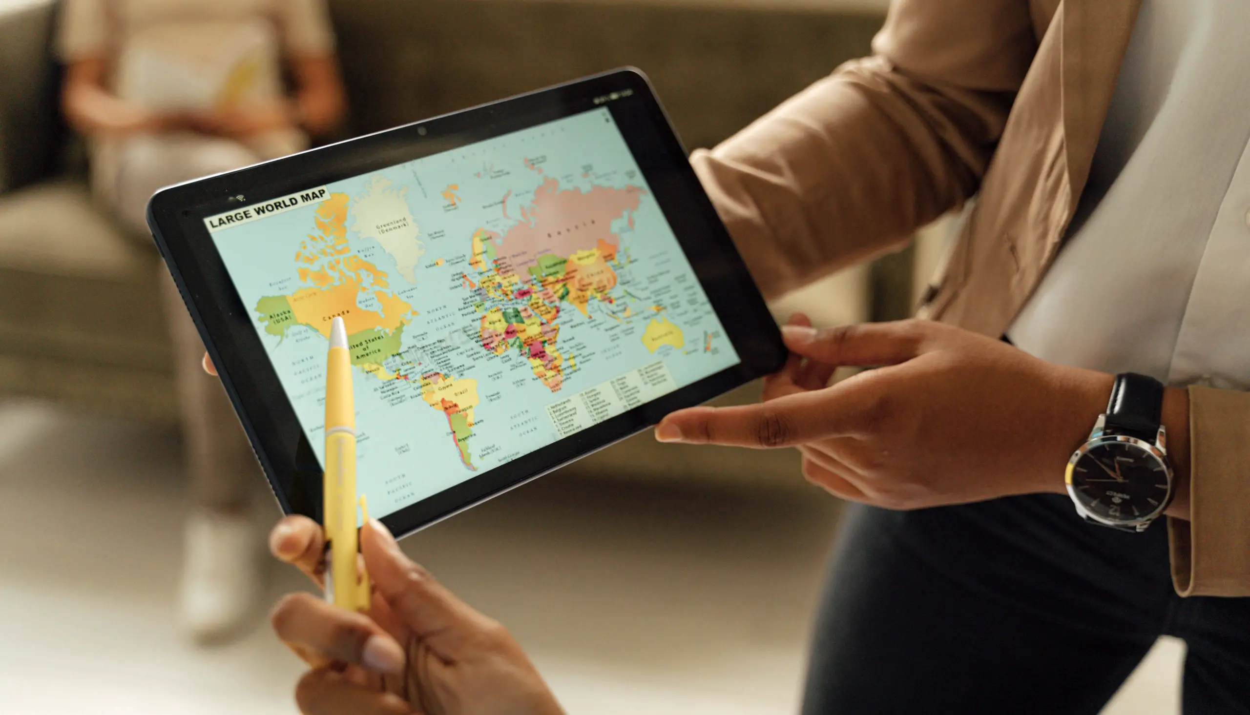 Close up photo of a person holding a tablet computer showing the world map
