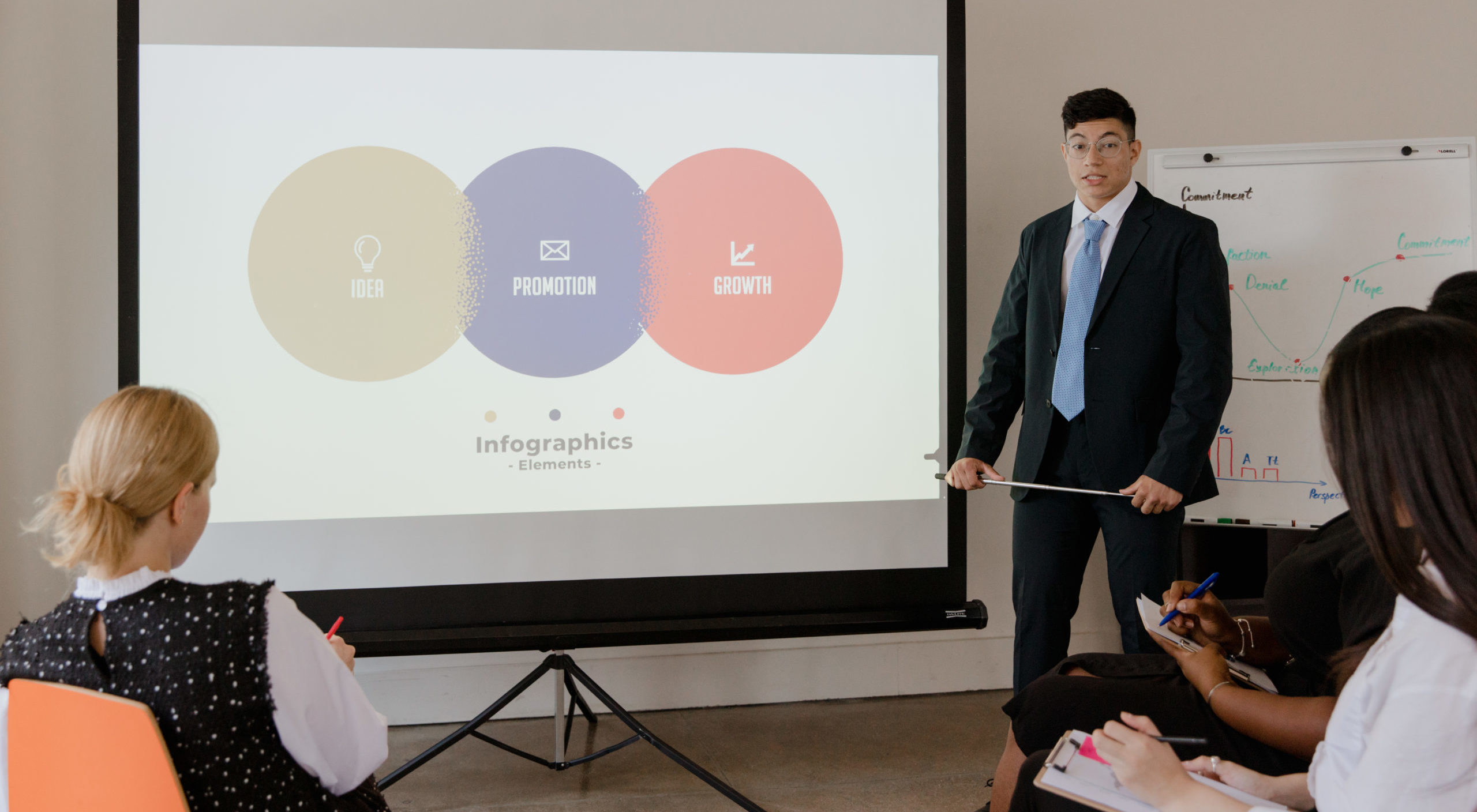 Man in black suit standing near black and white projector screen