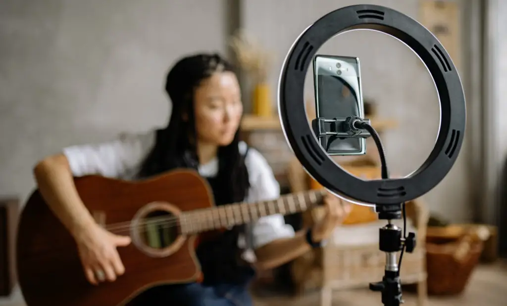 Ring light and smartphone in front of a girl playing guitar