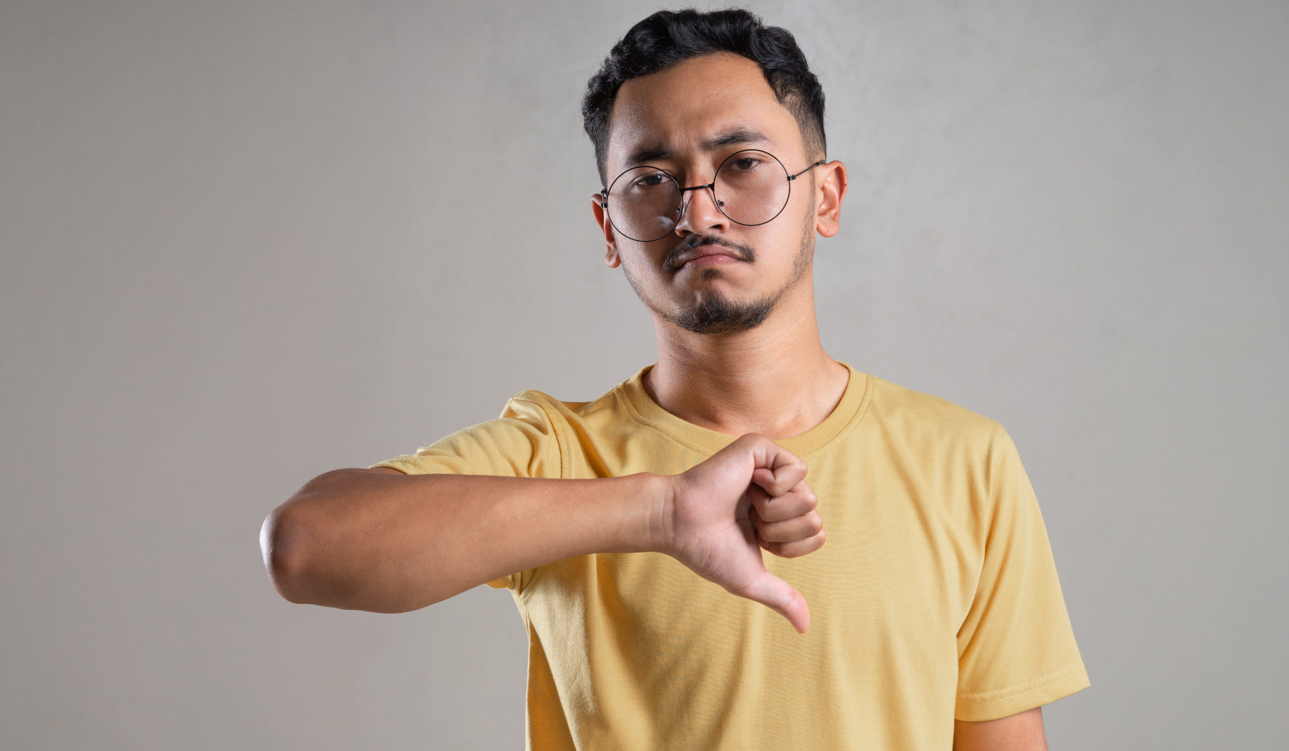 A man wearing eyeglasses doing thumbs down