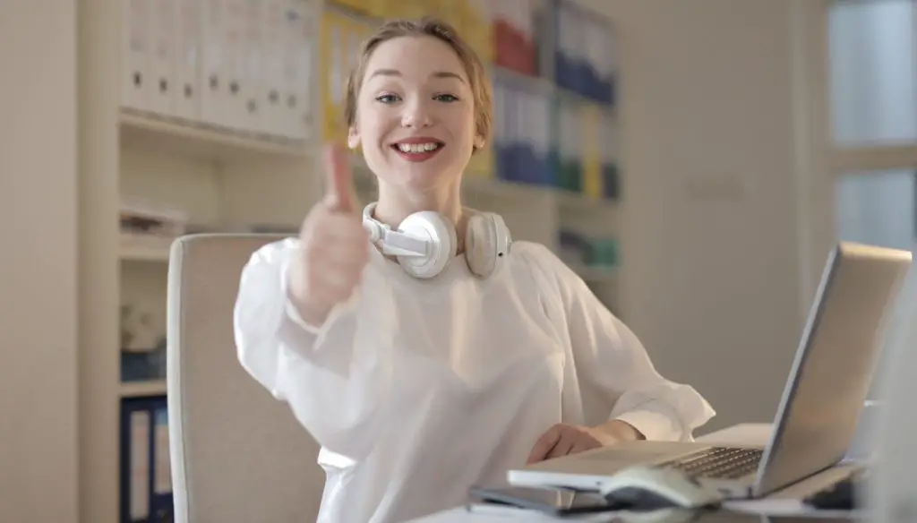 Woman wearing white top while doing thumbs up
